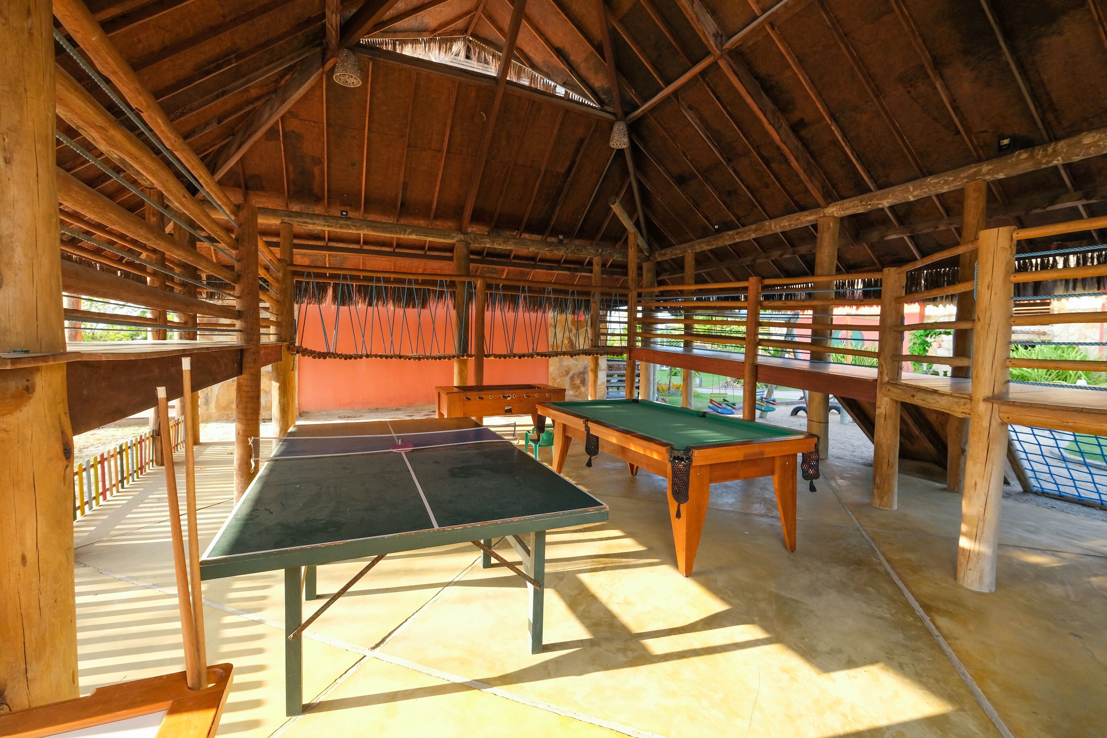 An indoor ping pong table area with wooden beams and a high ceiling.