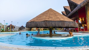 A swimming pool with thatched-roof structures, surrounded by lounge chairs and a tropical setting. - Carnaubinha Praia Resort (Luis Correia)