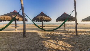 A beach with thatched umbrellas and a hammock. - Carnaubinha Praia Resort (Luis Correia)