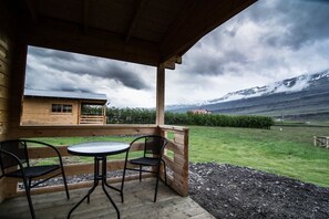 Une cabane en bois dotée d’un balcon, de deux chaises et d’une table.