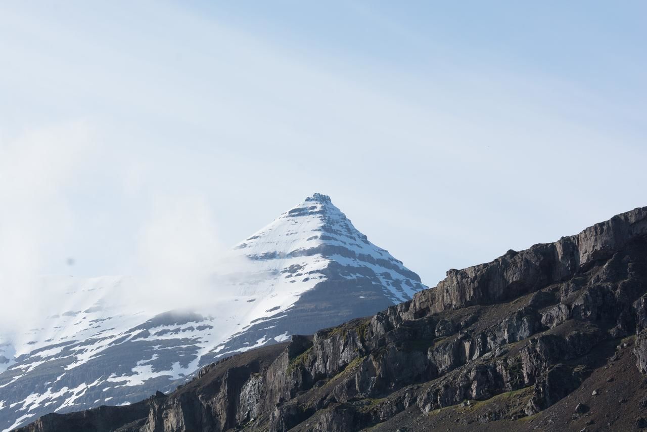 Ett snötäckt berg med en bergig förgrund.