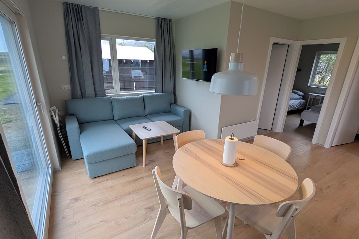 Ett modernt vardagsrum med en ljusblå soffa, ett matbord i trä med stolar och en platt-TV som är monterad på väggen.