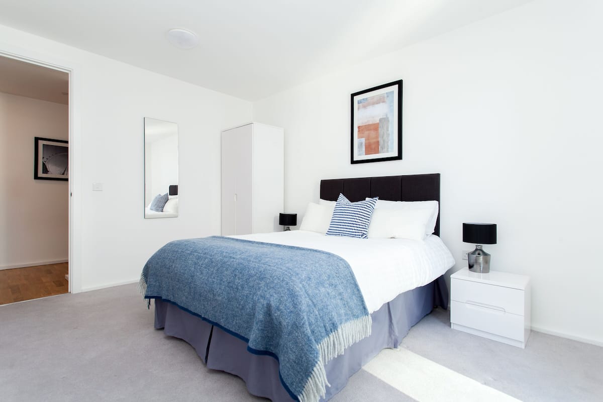 Une chambre à coucher moderne, avec un lit, des tables de chevet, une armoire et un tableau encadré au mur.