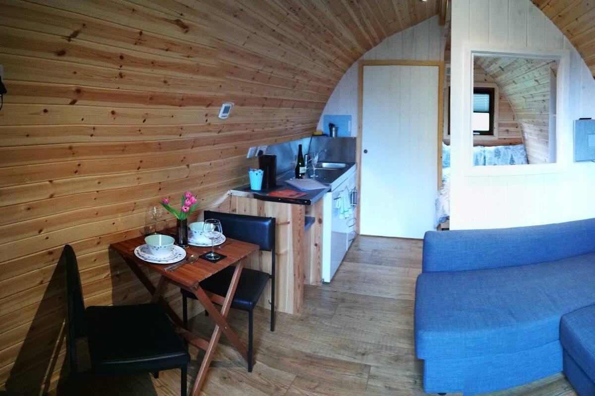 Un intérieur de chalet chaleureux avec un coin repas, un canapé et une cuisine.