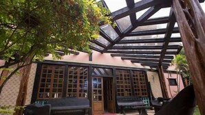A building with a covered patio area, featuring a bench and a table.