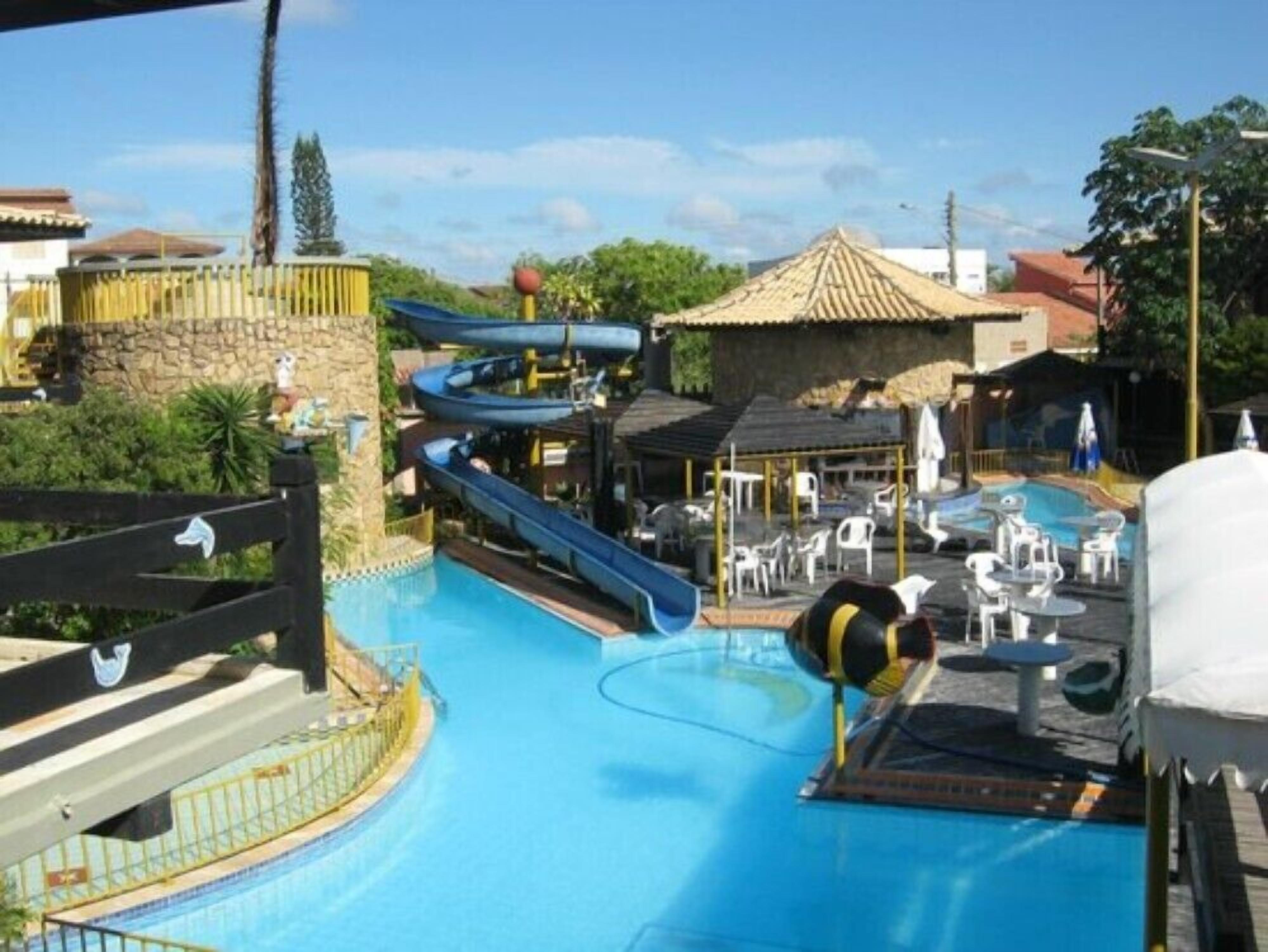 A swimming pool with a water slide and a small pool area with lounge chairs.