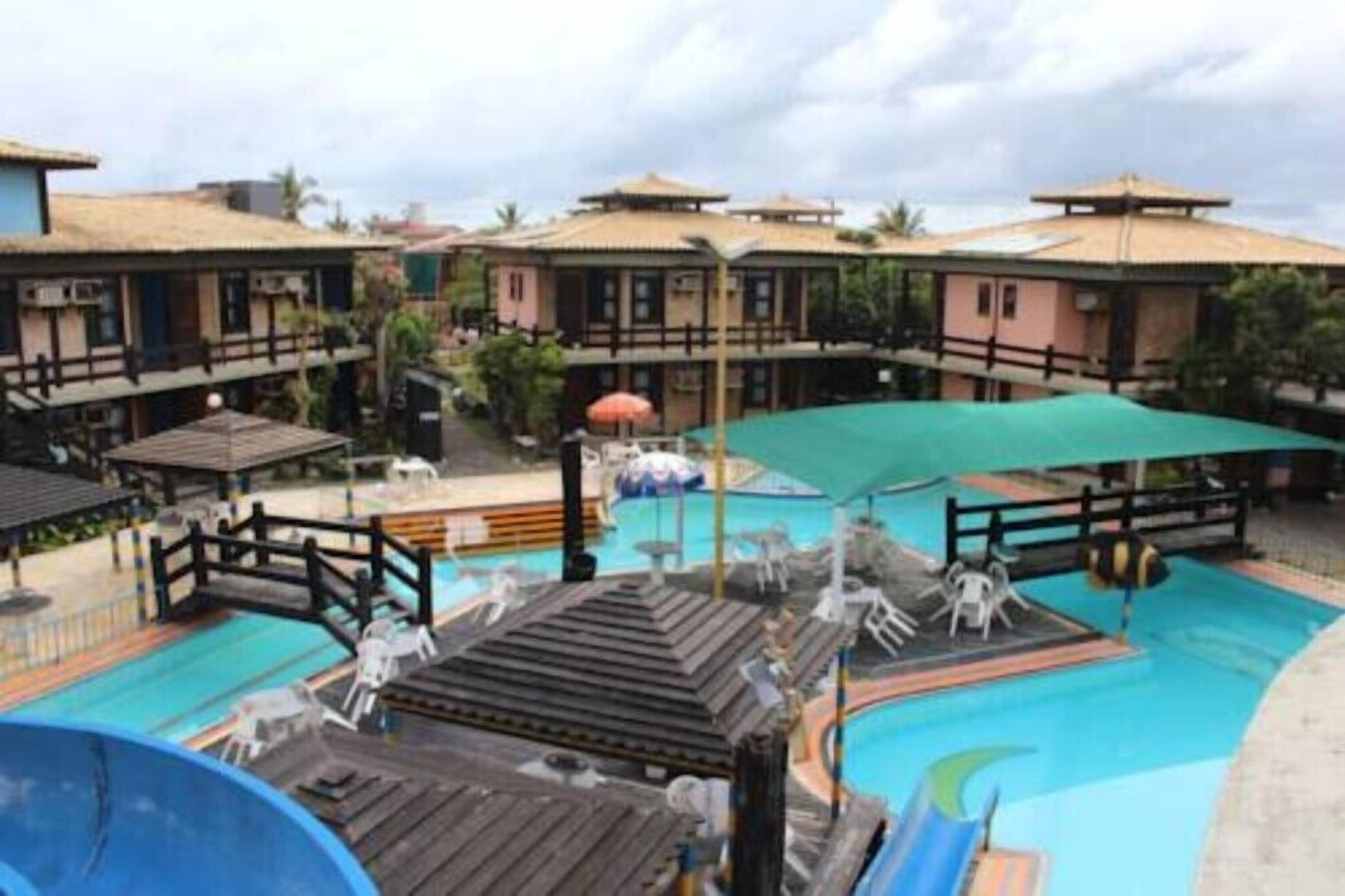 A resort with a swimming pool, wooden deck, and multiple buildings with balconies.