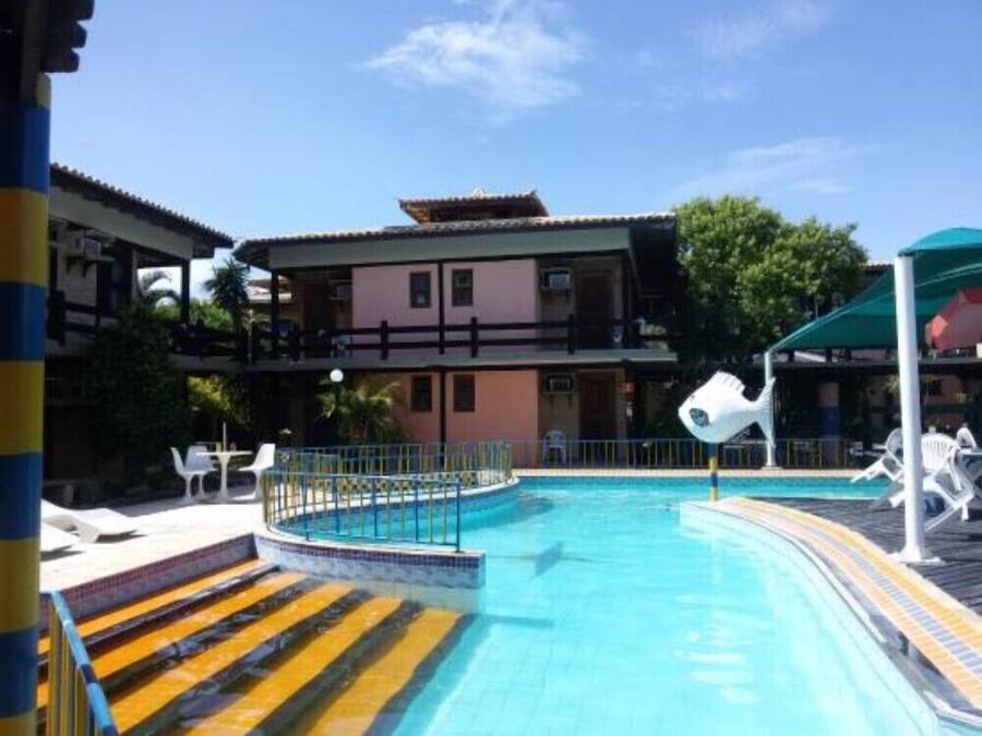 A swimming pool with a blue water feature, a multi-story building with balconies, and outdoor seating areas.