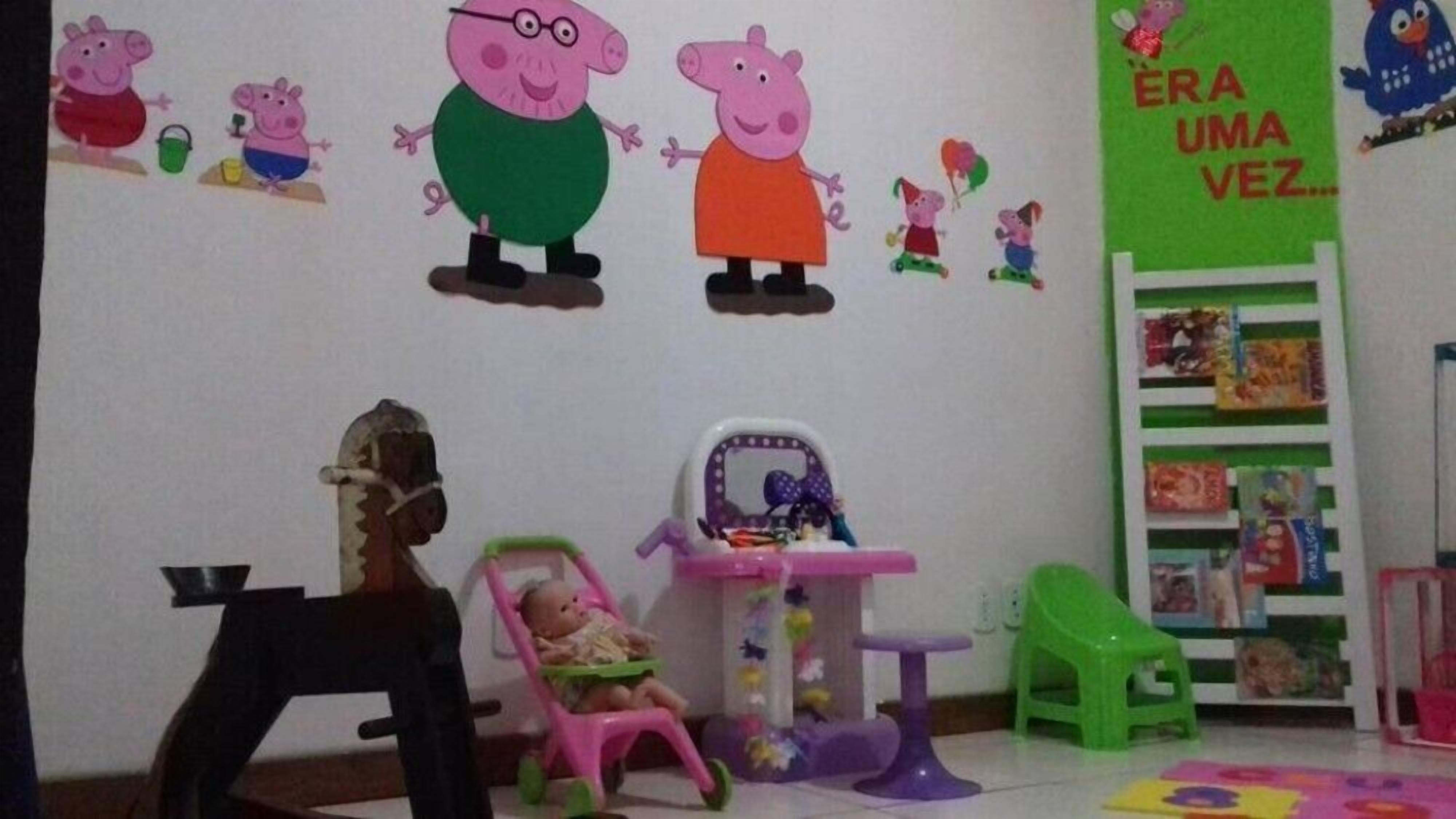 Una sala de juegos para niños con una pared decorada con personajes de dibujos animados, una mesita, una silla y una estantería.