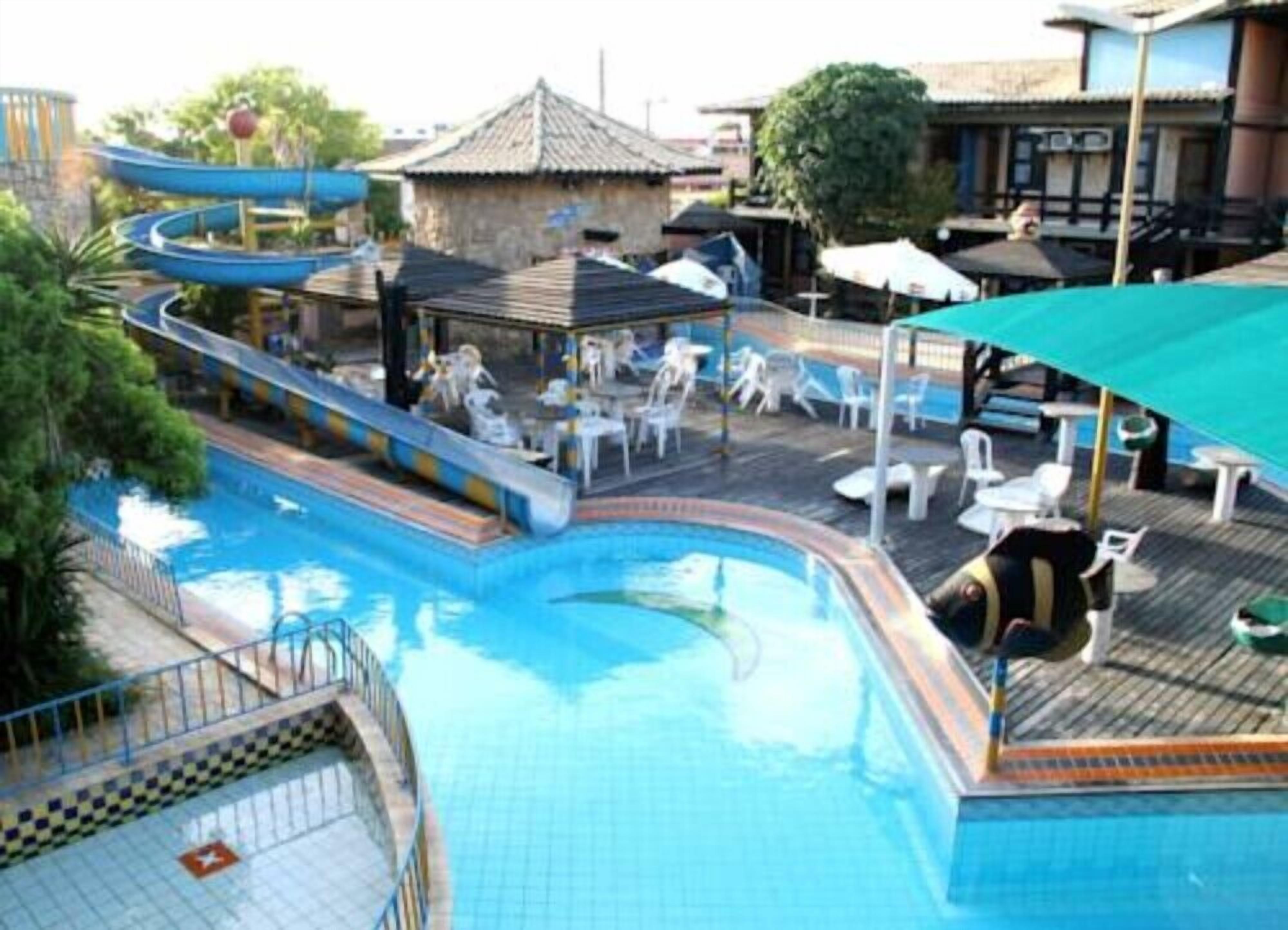 A swimming pool with a slide, lounge chairs, and umbrellas.