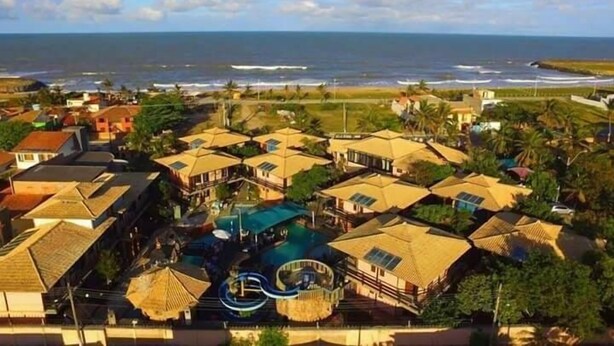 A coastal resort with multiple bungalow-style buildings, a central pool area, and a view of the ocean.