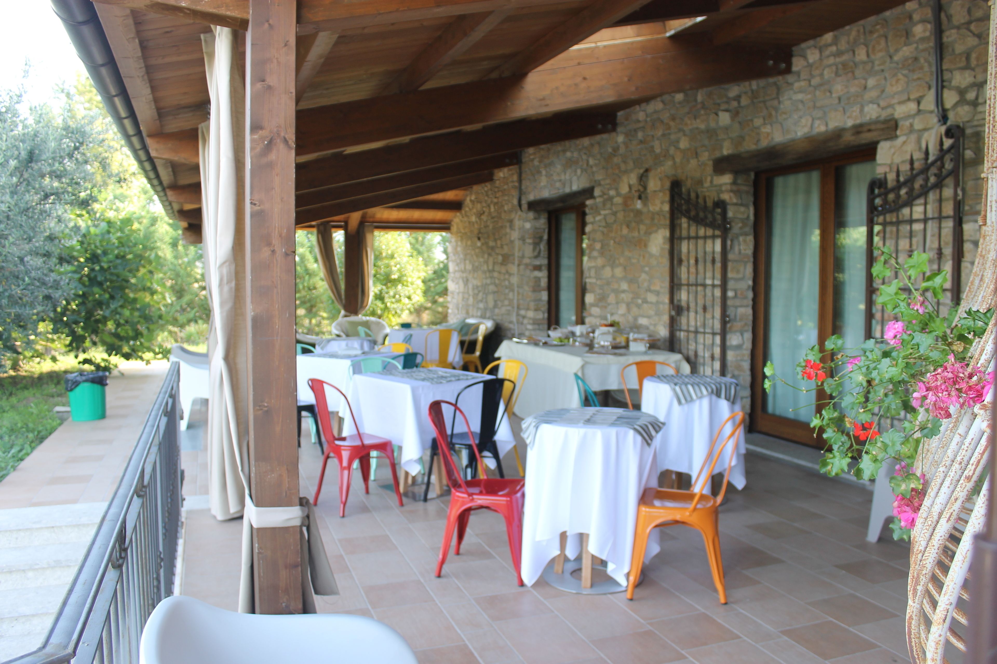 Une terrasse extérieure avec des tables et des chaises, des murs en pierre et une vue sur la verdure.