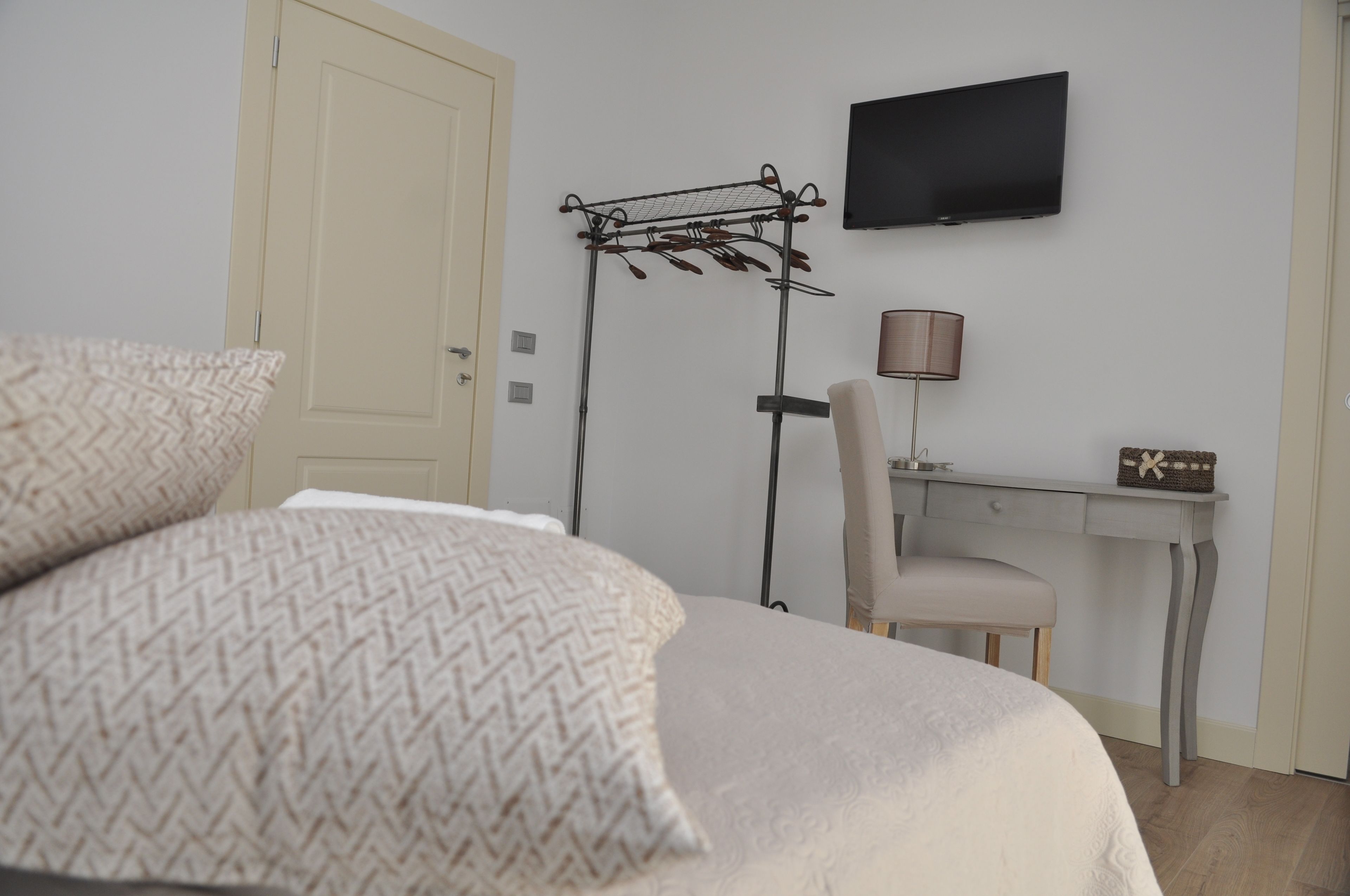 A bedroom with a bed, a desk, a chair, a TV, and a lamp.