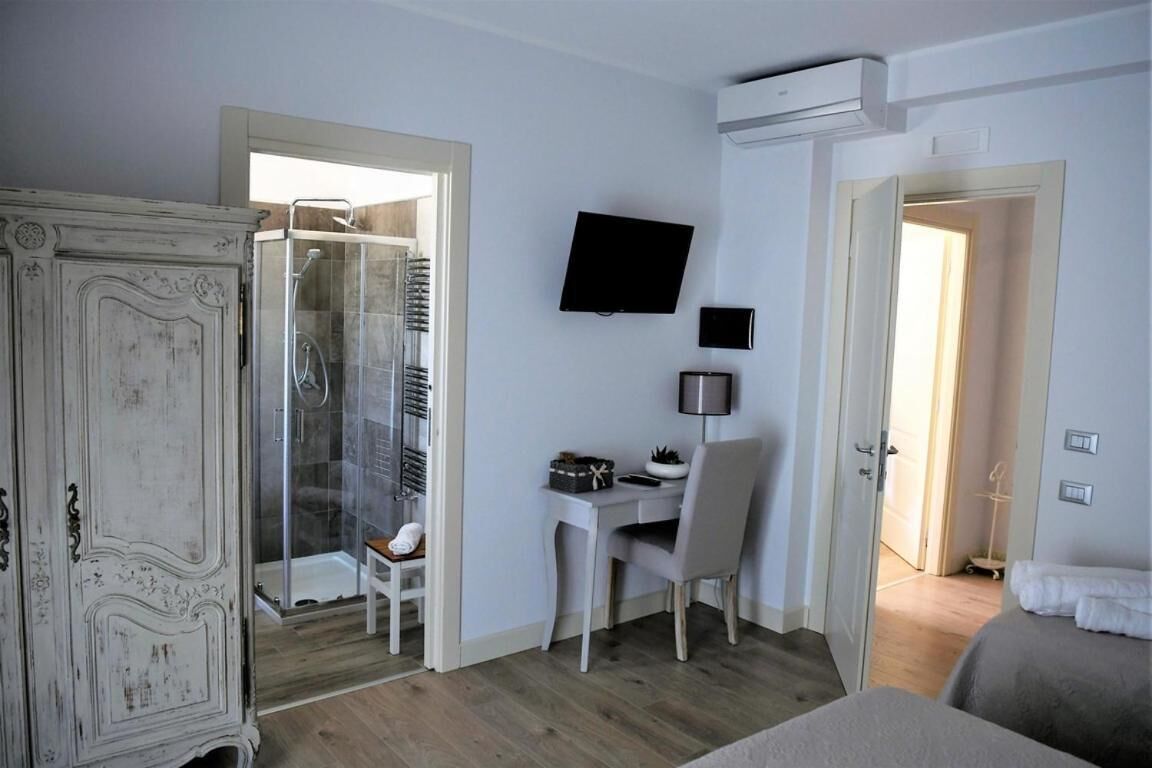 A hotel room with a wardrobe, a desk with a chair, a TV, and a bed.