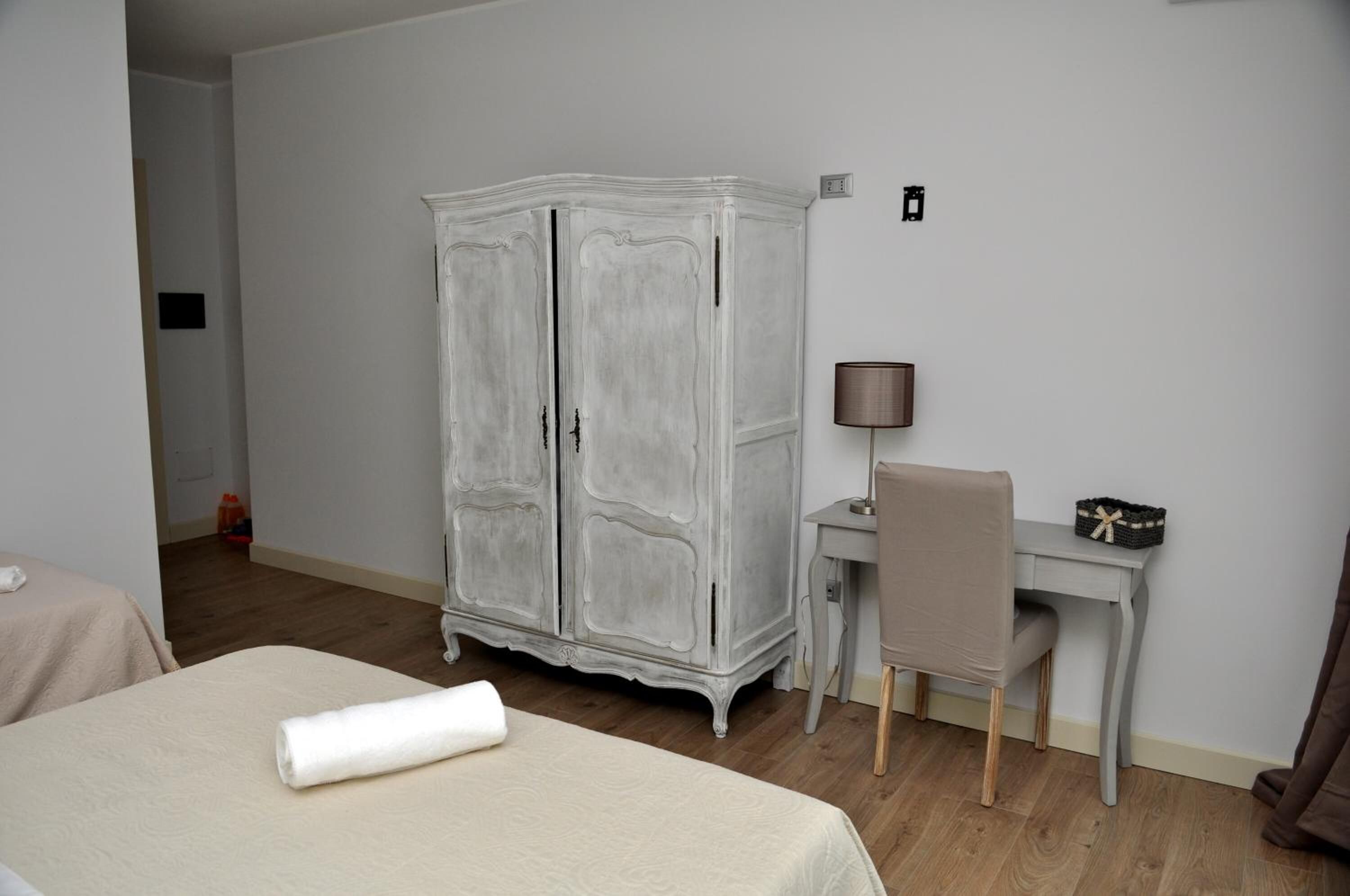Quarto de hotel com cama, escrivaninha, cadeira e guarda-roupa.