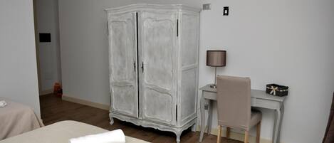 A hotel room with a bed, a desk, a chair, and a wardrobe.