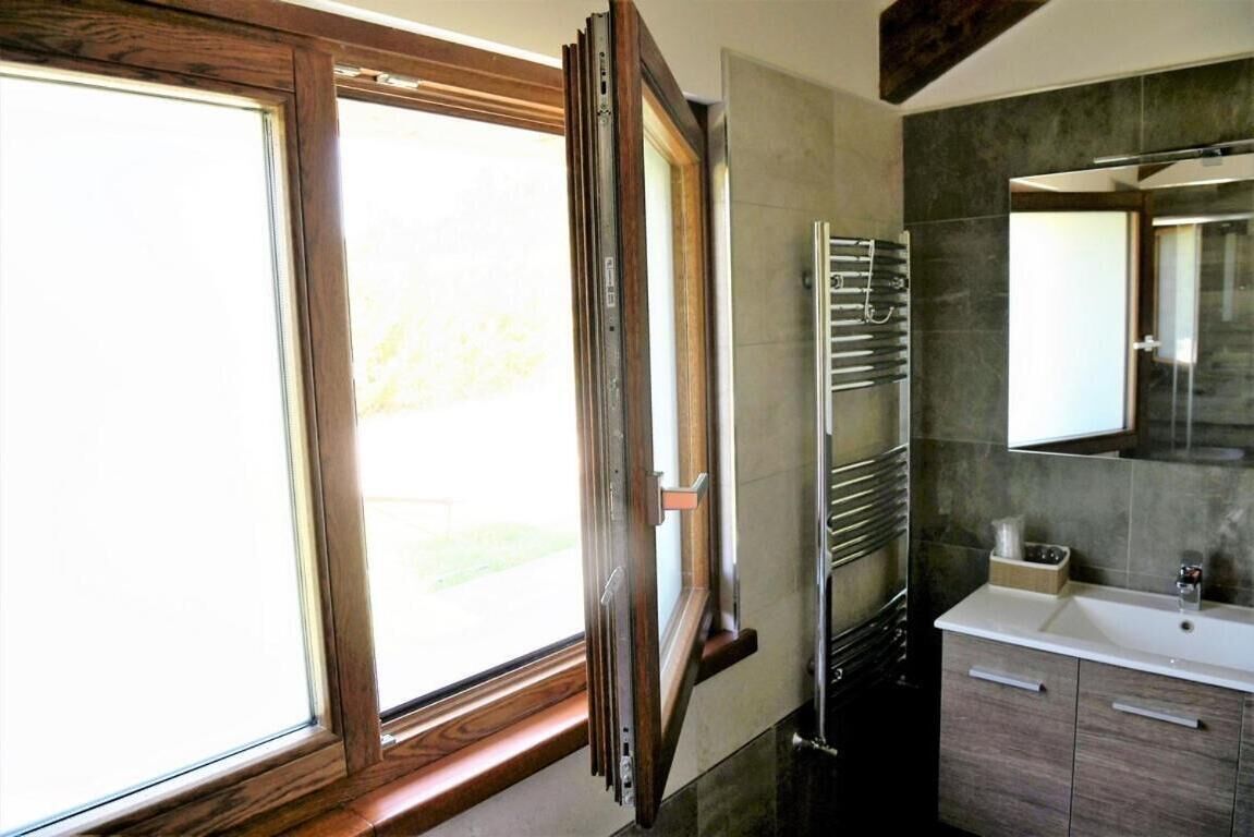 A bathroom with a large window, a towel rack, a sink, and a mirror.