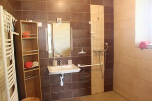 Een badkamer met wastafel, spiegel, handdoekhouder en douche.