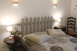 Een slaapkamer met een bed, twee nachtkastjes, een stoel en wandlampen.