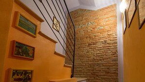 Eine Treppe mit einer Backsteinwand, gerahmten Kunstwerken und einer Leuchte.