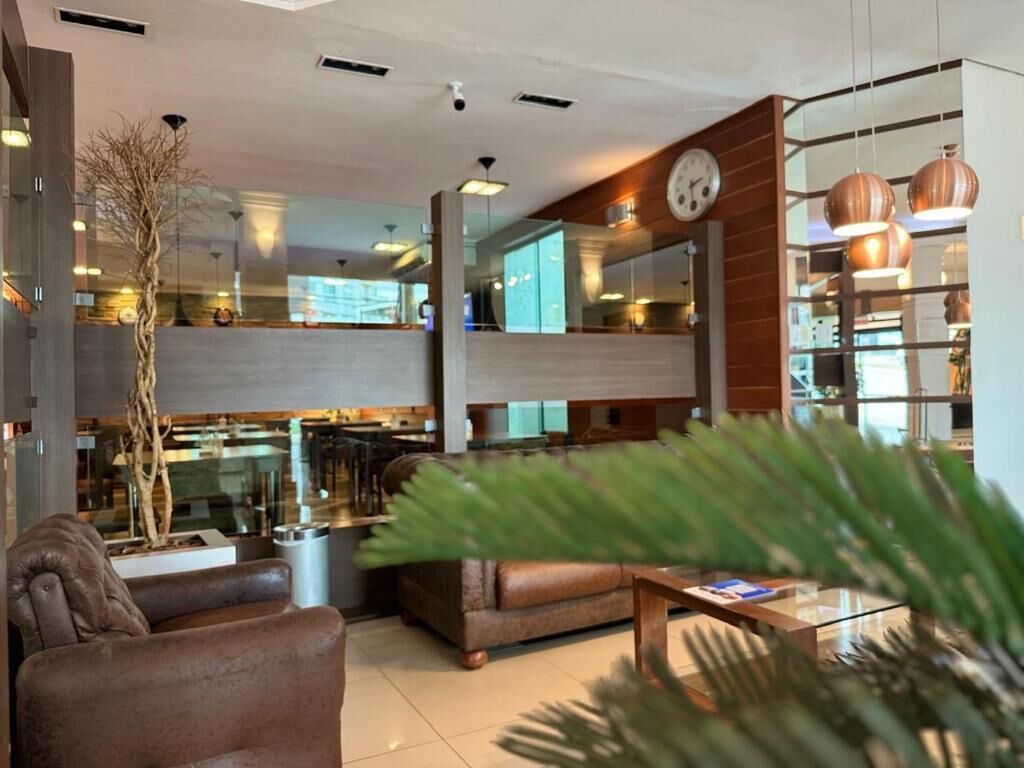 Um saguão de hotel moderno com área de estar, um relógio e vista para a cozinha.