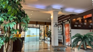 Eine geräumige Lobby mit einer zentralen Säule, einem Empfangsbereich und einer Treppe zu den oberen Stockwerken.