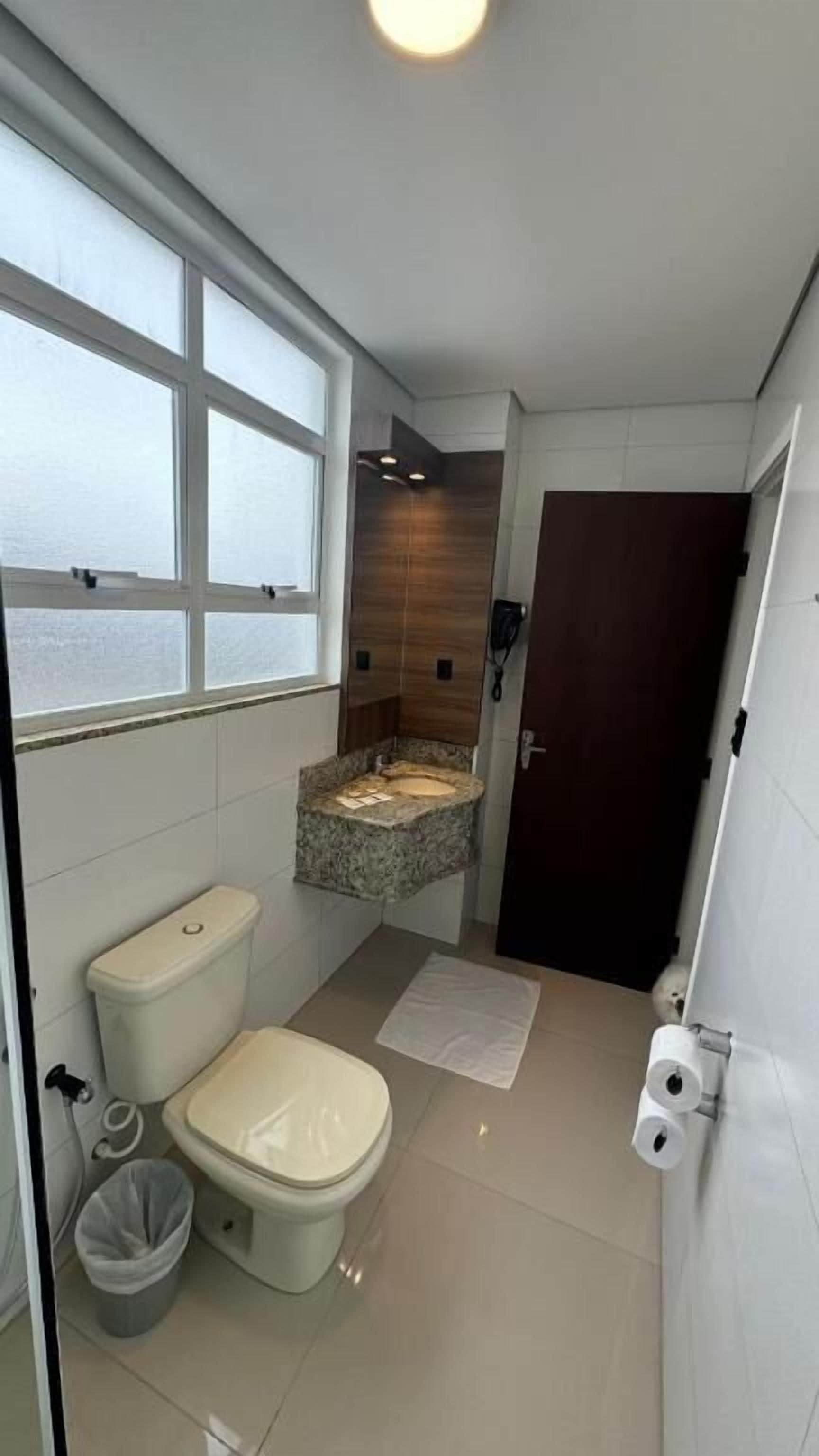 A compact bathroom with a toilet, bidet, and window.