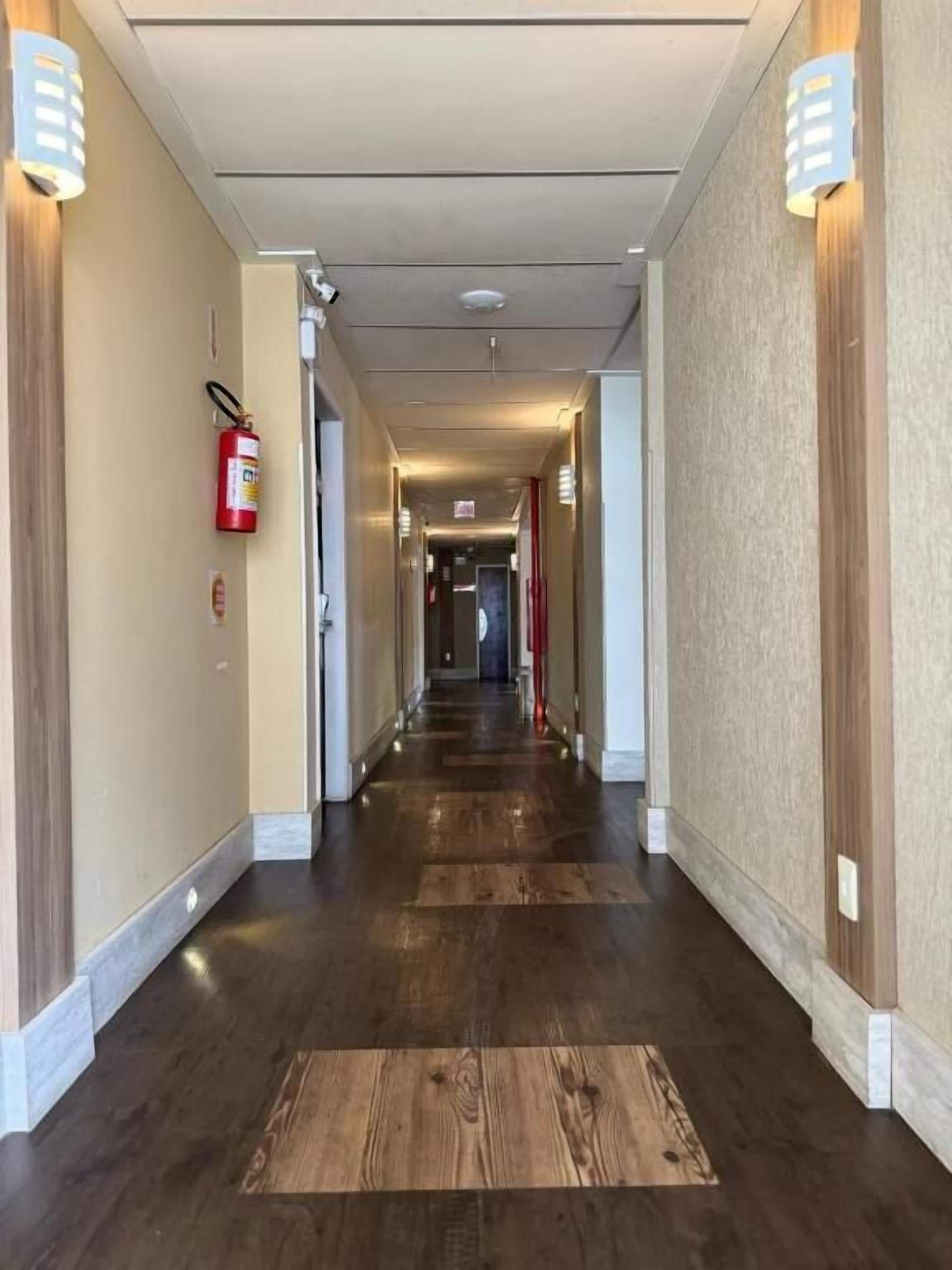Un pasillo de hotel con extintor, cámara de seguridad y detector de incendios en la pared.