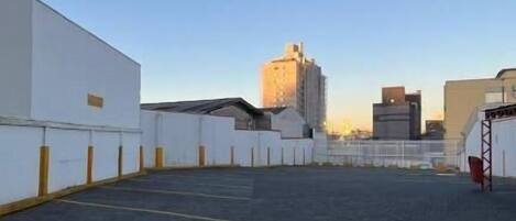 A rooftop parking area with a clear sky, a paved surface, and a white building on the left.