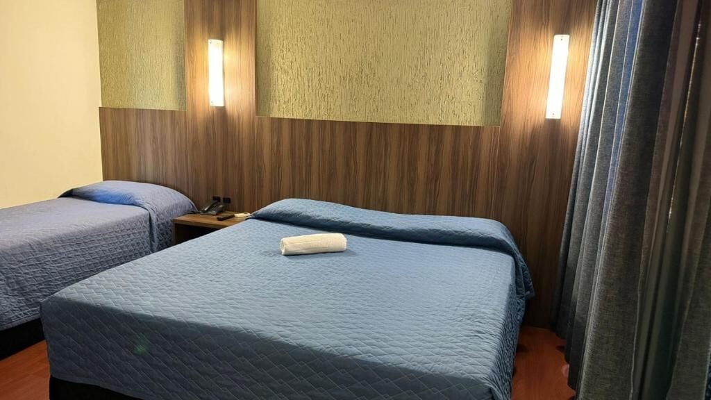 A hotel room with two beds, a wooden headboard, and a nightstand with a phone.