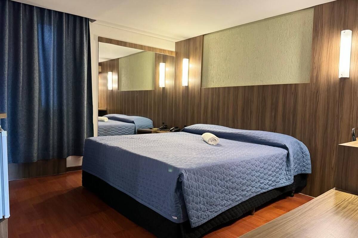 A hotel room with two beds, a large mirror, wooden paneling, and a wooden floor.