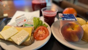 Ein Teller mit Käse, Tomate und einer Pfirsichfrucht.