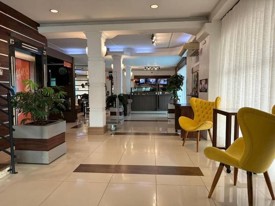 Um saguão de hotel com balcão de recepção, área de estar e vista para o restaurante.