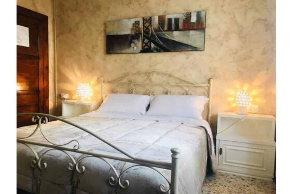Ein Schlafzimmer mit einem Bett, Nachttischen und einem Wandbild.