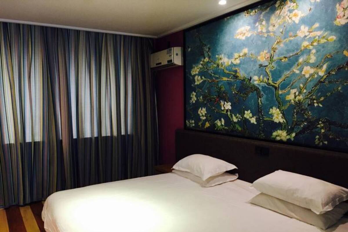 Une chambre d’hôtel avec un grand lit, des rideaux à rayures et une fresque florale sur le mur.