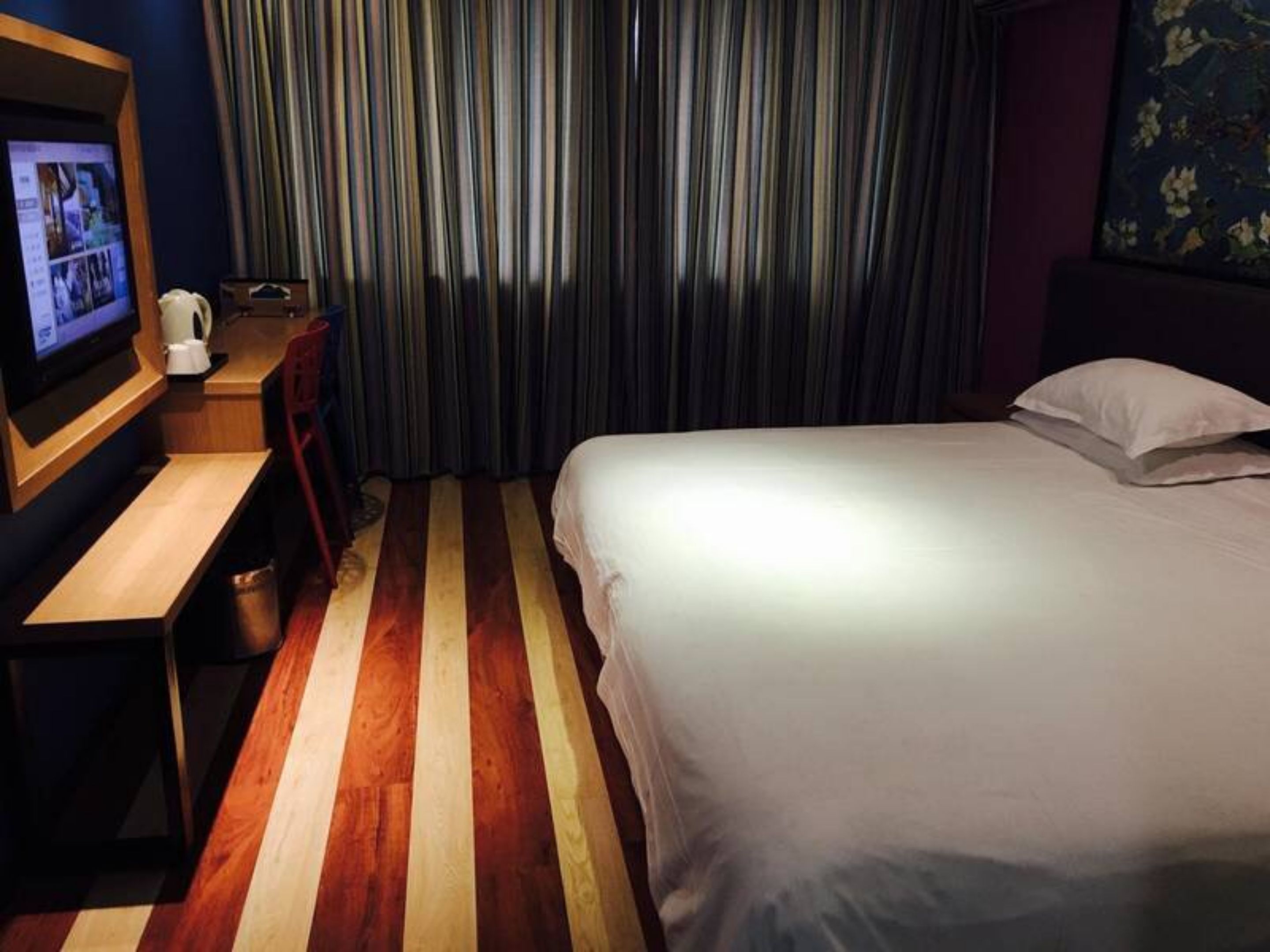 Een hotelkamer met een bed, een bureau, een televisie en een raam met gordijnen.