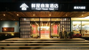 The exterior of Fresh House Hotel with a prominent entrance, a wooden facade, and a signboard displaying the hotel name.