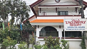Un bâtiment à deux étages, sur lequel on peut lire une enseigne indiquant « Villa Tagumpay Resort », et qui précise que l’établissement est ouvert 24 heures sur 24 et que l’eau des piscines est renouvelée quotidiennement.