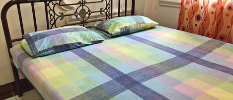 Una cama con un edredón colorido a cuadros y dos almohadas.