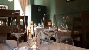 Ein Restaurantinneres mit gedeckten Tischen, klarem Glasgeschirr und einer dekorativen Glasvase.