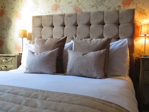 A neatly made bed with a tufted headboard, multiple pillows, and two bedside tables with lamps. - The Capon Tree Town House (Jedburgh)