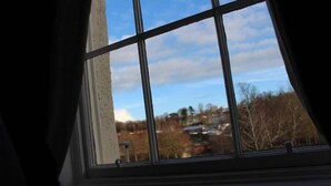 Ein Fenster mit Blick auf ein Gebäude und Bäume.