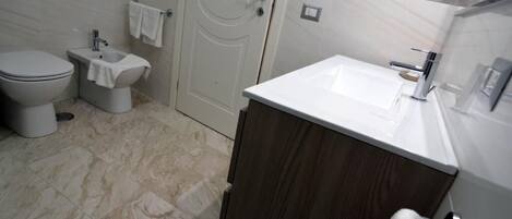 Une salle de bain moderne équipée de toilettes, d’un bidet et d’un lavabo.
