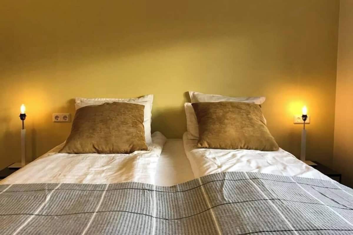 A double bed with a striped bedspread, two pillows, and bedside lamps.