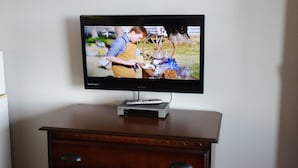 A television on a wooden dresser in a hotel room. - Hoosier Inn (Portland)