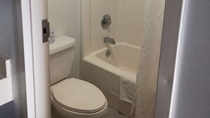 A bathroom with a toilet, a bathtub, and a shower curtain. - Hoosier Inn (Portland)