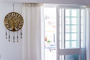 Una habitación con un ventanal grande, cortinas blancas y un adorno en la pared.