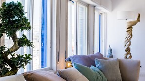 Een woonkamer met een groot raam, een potplant, een bank en een decoratief beeld.