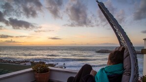 Een balkon met uitzicht op de oceaan bij zonsondergang.