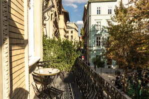 A narrow outdoor corridor with a small table and chairs, flanked by buildings with classical architecture and a tree in the center. - Hotel Collect – Adults Only (Budapest)